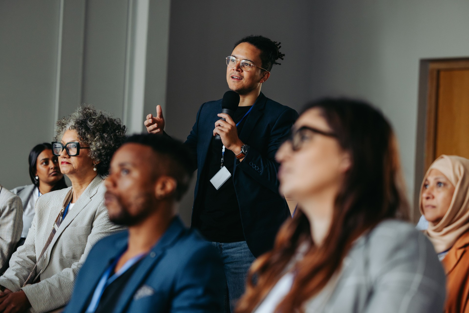 Businessman asking question during diverse conference workshop presentation